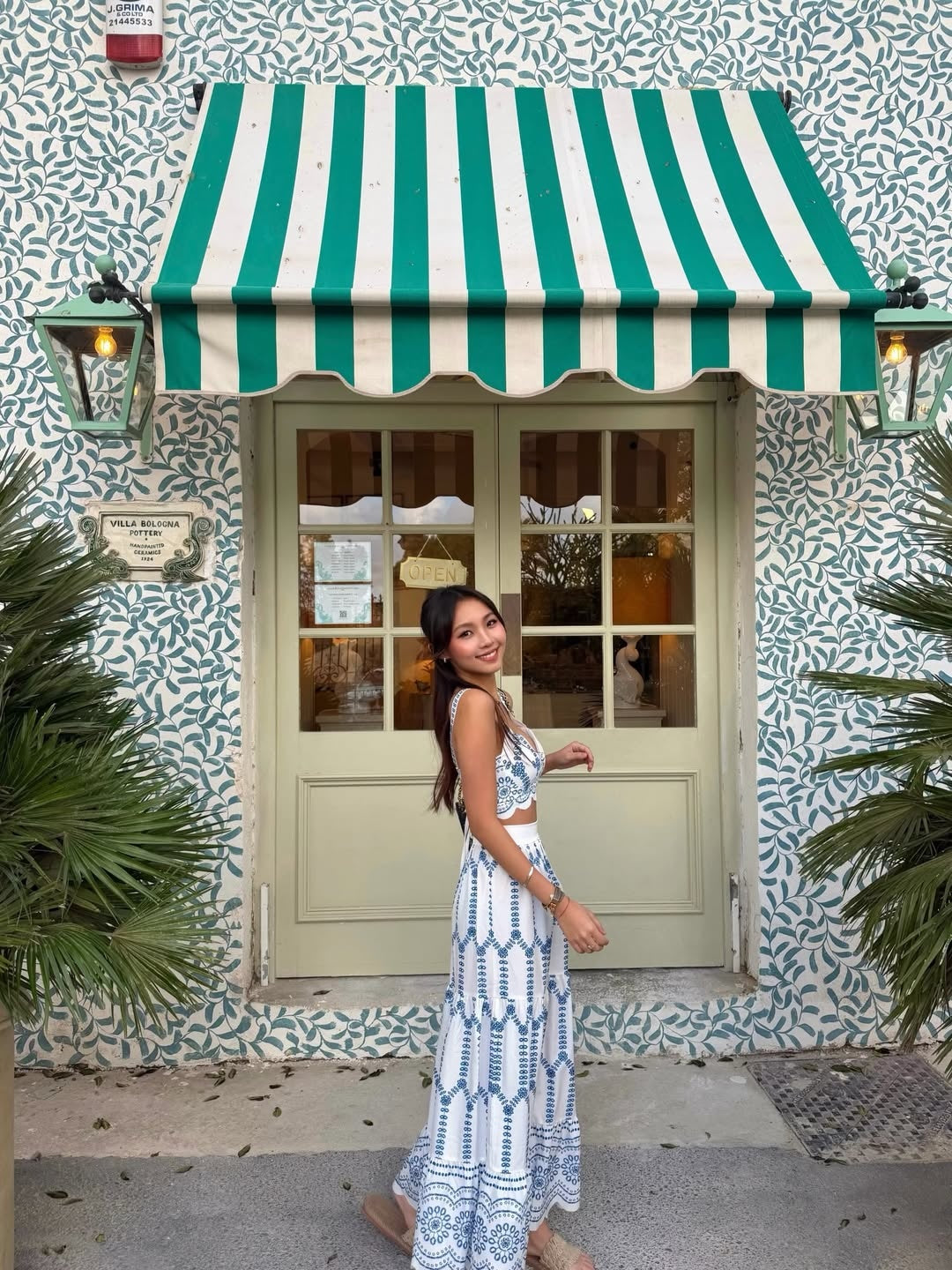 Woman standing in front of a building with a green and white striped awning.